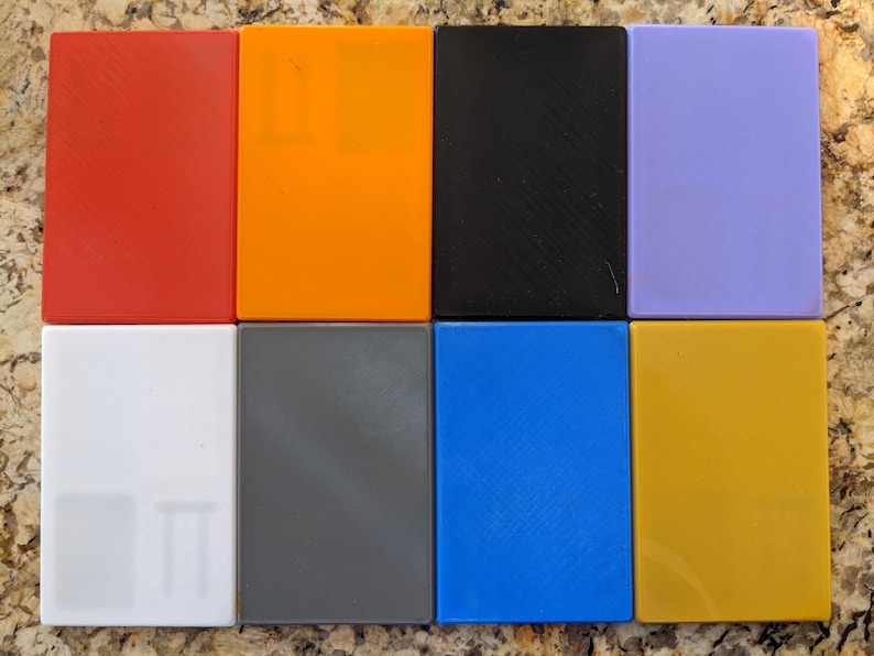May include: Eight square tiles in different colors: red, orange, black, purple, white, gray, blue, and yellow.