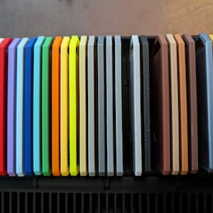 May include: A set of 25 colorful silicone phone cases in a variety of colors, including pink, red, blue, green, yellow, orange, gray, brown, and black. The cases are arranged in a row and are all the same size.