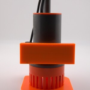 May include: An orange and black device with a rectangular orange component and a cylindrical black body. The device has a series of vertical orange bars at the base and black wires extending from the top. The device is on a white background.