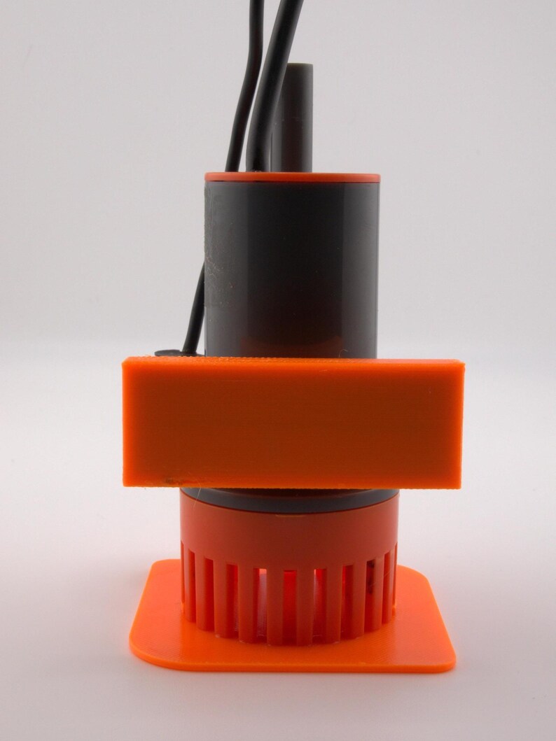 May include: An orange and black device with a rectangular orange component and a cylindrical black body. The device has a series of vertical orange bars at the base and black wires extending from the top. The device is on a white background.