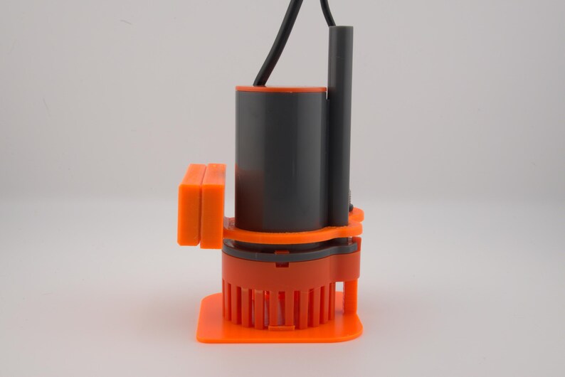 May include: An orange and gray submersible pump with a black power cord. The pump has a cylindrical gray body, an orange base, and an orange rectangular component on the side. The base has vertical orange fins.