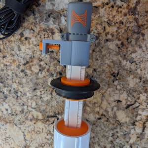 May include: A gray and orange water level sensor with a black cord and a clamp. The sensor has a ruler with markings from 10 to 32.