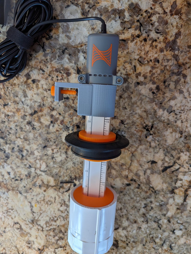 May include: A gray and orange water level sensor with a black cord and a clamp. The sensor has a ruler with markings from 10 to 32.