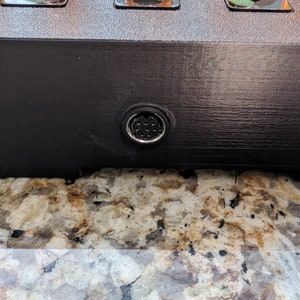 Puede incluir: Primer plano de un dispositivo electr&oacute;nico negro con un conector redondo plateado en la parte inferior.