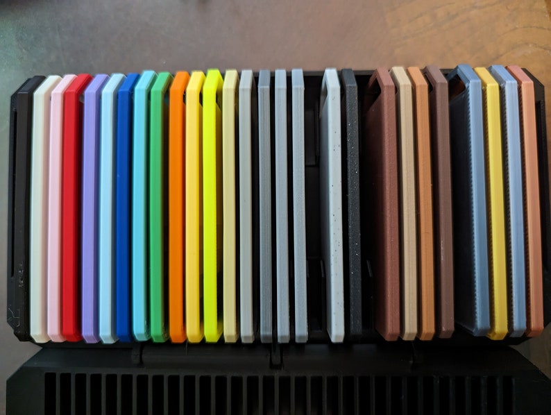 May include: A set of 25 colorful silicone phone cases in a variety of colors, including pink, red, blue, green, yellow, orange, gray, brown, and black. The cases are arranged in a row and are all the same size.