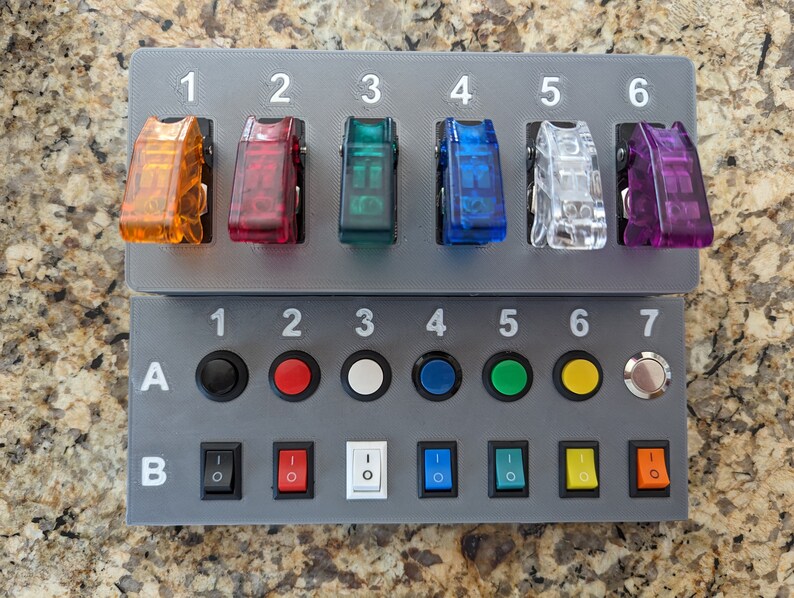 May include: A gray panel with two rows of switches and buttons. The top row has six toggle switches labeled 1 through 6. The bottom row has seven buttons labeled 1 through 7, and two rows of toggle switches labeled A and B.