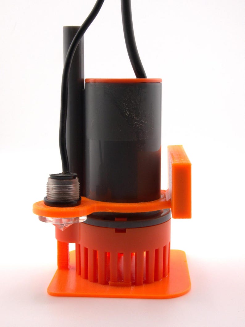 May include: An orange and black submersible pump with a black power cord. The pump has a cylindrical body with an orange base and a series of vertical slots. The top of the pump is black with an orange rim.