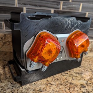 May include: A black plastic box with two orange and silver pumps labeled "DOS" mounted on the front.
