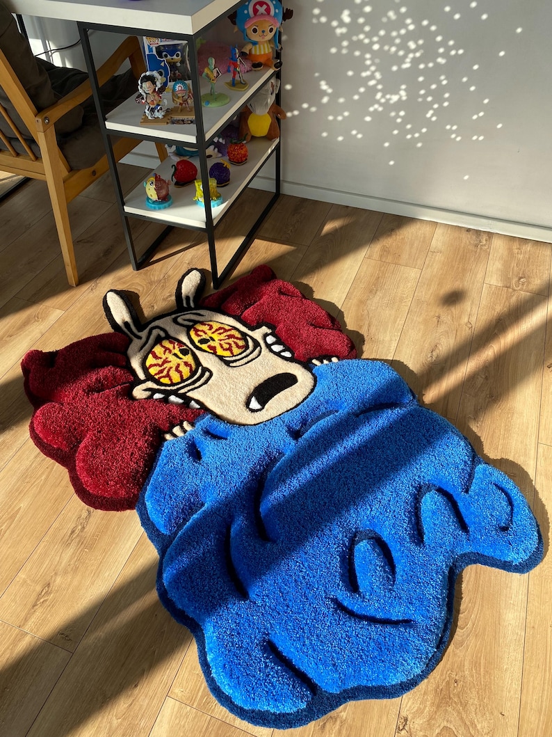 May include: A blue and red rug with a cartoon character design. The character has large eyes and is holding its head. The rug is made of a soft, plush material.