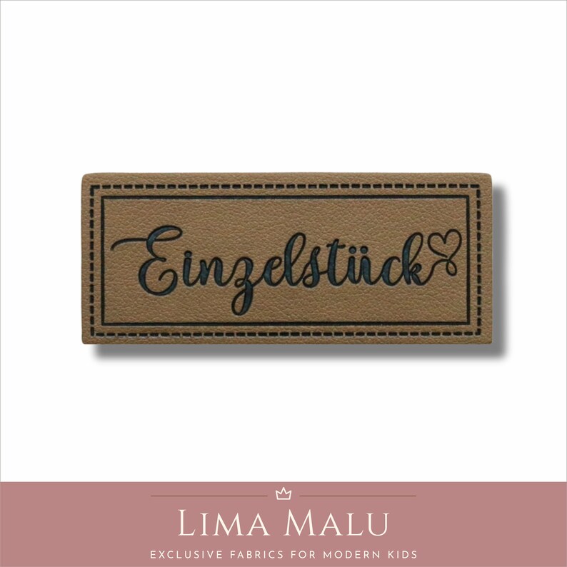 May include: A brown leather label with a black stitched border and the text "Einzelst&uuml;ck" in black cursive lettering with a small heart symbol.