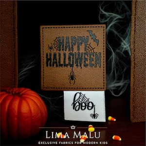 Könnte beinhalten: Ein braunes quadratisches Patch mit den Worten "HAPPY HALLOWEEN" in Schwarz, einer Fledermaus und Spinnennetz-Designs. Ein weißes Patch mit dem Wort "boo" und einem Spinnennetz. Ein orangefarbener Kürbis und Zuckermais sind ebenfalls zu sehen.