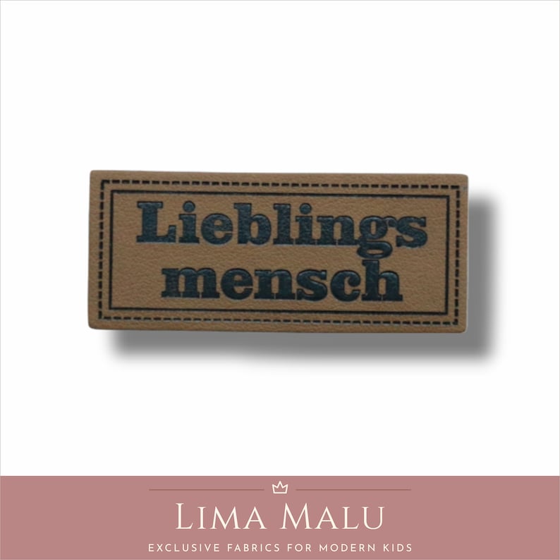 May include: A brown leather patch with a stitched border. The text "Lieblingsmensch" is printed in black.