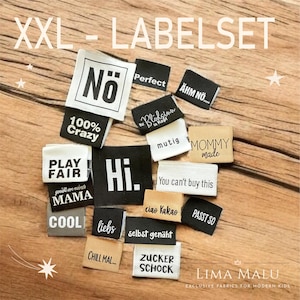 Könnte beinhalten: Eine Sammlung von Stoffetiketten in verschiedenen Farben mit Aufschriften wie "Hi", "Perfect" und "Mommy Made". Die Etiketten sind in verschiedenen Größen und Formen gehalten, mit weißem Text auf schwarzen, beigen und weißen Hintergründen. Das Bild enthält auch den Text "XXL - LABELSET".