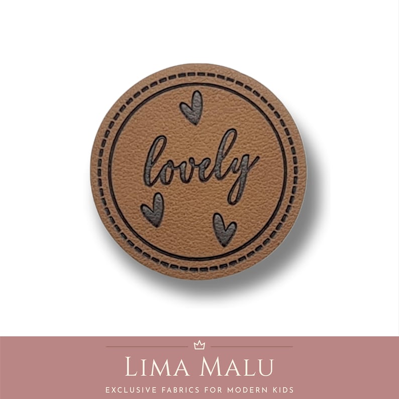May include: Brown leather patch with a stitched border and the word "lovely" in black script. Three small black hearts are arranged around the word.