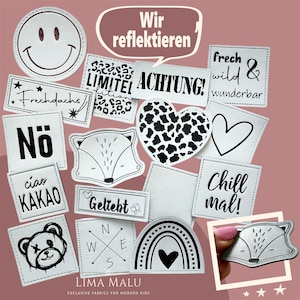 Può includere: Una collezione di toppe in tessuto bianco con bordi cuciti neri e vari disegni. Include una faccina sorridente, una volpe, un cuore e testo come "ACHTUNG!" e "Chill mal!". Le toppe sono per bambini moderni.