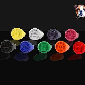 May include: Ten colorful rings with different symbols, each ring is a different color: black, blue, white, yellow, green, orange, red, purple, and two shades of red. The rings are arranged in a semi-circle on a black surface.  Big Dawg Forge.