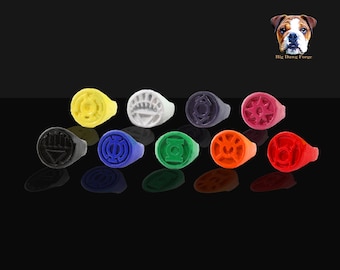 May include: Ten colorful rings with different symbols, each ring is a different color: black, blue, white, yellow, green, orange, red, purple, and two shades of red. The rings are arranged in a semi-circle on a black surface.  Big Dawg Forge.