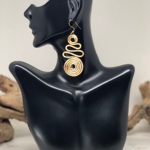 Gioielli avvolti con filo metallico. Orecchini a spirale dorati e sinuosi.