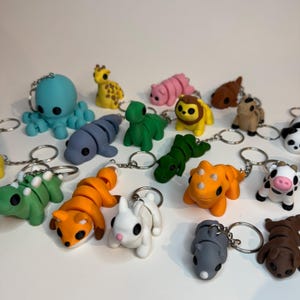 May include: A collection of colorful animal-shaped keychains. The keychains include an octopus, giraffe, hippo, lion, and more. Each keychain is made of a smooth material and features a silver keyring.
