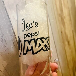 Puede incluir: Un vaso de vidrio transparente con un dise&ntilde;o en blanco y negro que dice "Lee's Pepsi Max".