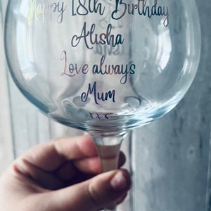 May include: A clear glass gin glass with a gold and silver inscription that reads "Happy 18th Birthday Alisha Love always Mum xxx".