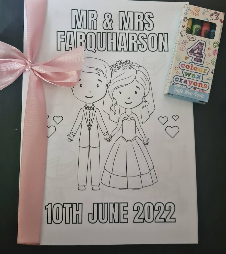 May include: A white coloring book with a pink ribbon and a box of crayons. The cover features a cartoon bride and groom with the text "MR & MRS FARQUHARSON" and "10TH JUNE 2022".