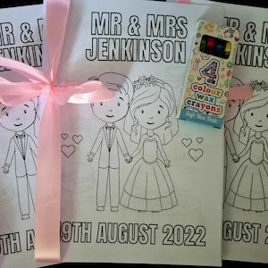 May include: Two coloring book pages with a bride and groom, a pink ribbon, and a box of four color wax crayons. The pages say "Mr. & Mrs. Jenkinson" and "19th August 2022".