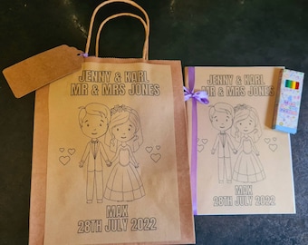 May include: A brown paper bag with handles, a coloring book, and a pack of crayons. The bag and coloring book both have the text "Jenny & Karl Mr & Mrs Jones" and "Max 28th July 2022". The coloring book features a cartoon bride and groom.
