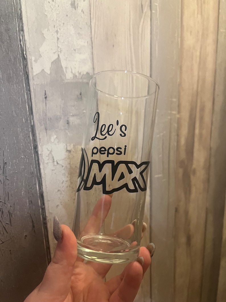 Puede incluir: Un vaso transparente con un dise&ntilde;o negro que dice "Lee's Pepsi Max".