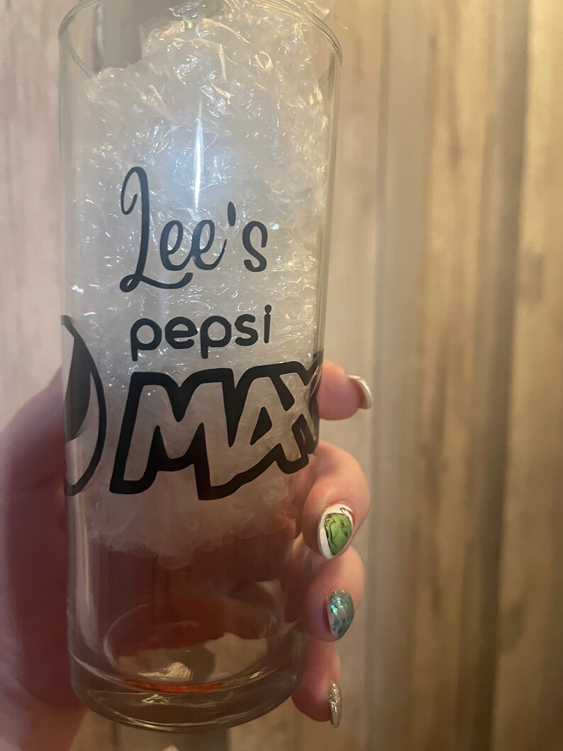 Puede incluir: Un vaso de vidrio transparente con un dise&ntilde;o en blanco y negro que dice "Lee's Pepsi Max".
