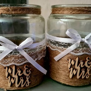 May include: Two clear glass jars decorated with burlap, lace, and white ribbon. Each jar has a wooden sign that says "Mr. & Mrs."