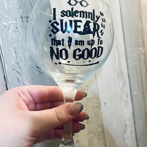May include: A clear glass wine glass with a black vinyl decal that reads "I solemnly swear that I am up to no good".