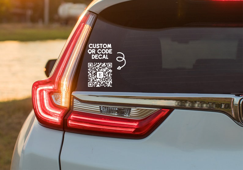 May include: A white custom QR code decal with the text "CUSTOM QR CODE DECAL" on a silver car.