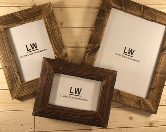May include: Three rustic wooden picture frames in different sizes, all with a dark brown stain. Each frame has a white mat and features the text "LW LAURELTON WORKSHOP" printed in black.