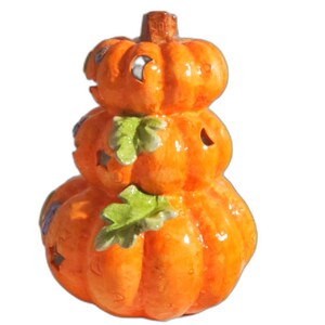 May include: A stacked orange ceramic pumpkin decoration with cut-out star shapes and green leaf accents. The pumpkin has a glossy finish and is designed for Halloween or autumn decor.