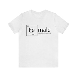May include: White t-shirt featuring a black graphic of the periodic table element for iron, Fe, with the text "female" and "The Original Iron Man" below it.