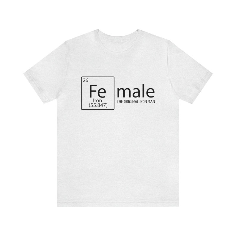 May include: White t-shirt featuring a black graphic of the periodic table element for iron, Fe, with the text "female" and "The Original Iron Man" below it.