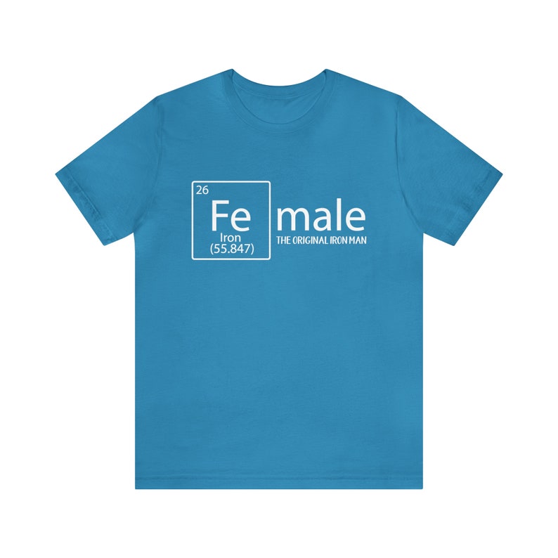 May include: A turquoise blue t-shirt with a white graphic of a periodic table element. The element is labelled "Fe" for iron and the text "male" is below it. The text "The Original Iron Man" is below the word "male".
