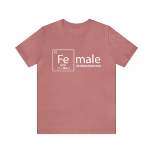 May include: A heather pink t-shirt with a white graphic of the periodic table element for iron, with the word "female" next to it and the text "The Original Iron Man" underneath.