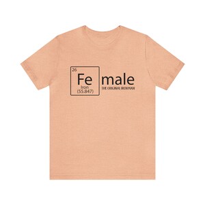 May include: A peach-coloured t-shirt with a black graphic of a periodic table element. The element is iron, with the symbol "Fe", atomic number 26, and atomic weight 55.847. The text "male" is written next to the element box, with the words "The Original Iron Man" underneath.