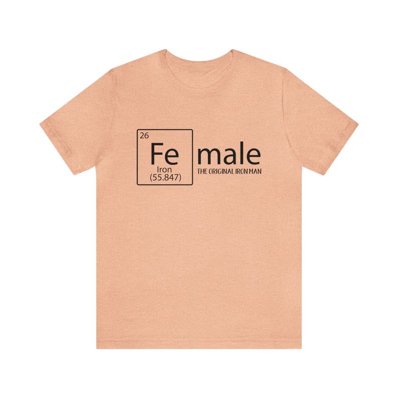 May include: A peach-coloured t-shirt with a black graphic of a periodic table element. The element is iron, with the symbol "Fe", atomic number 26, and atomic weight 55.847. The text "male" is written next to the element box, with the words "The Original Iron Man" underneath.