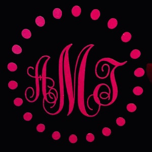 May include: A pink monogram with the letters "AJM" surrounded by a circle of pink dots on a black background.