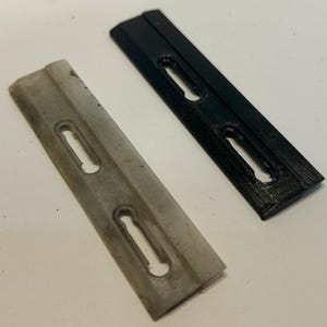 May include: Two plastic pieces with slots, one is white and the other is black. Both pieces have three slots.