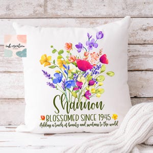 May include: White pillow with a floral design and the text "Shannon Blossomed Since 1945 Adding a touch of beauty and sweetness to the world".