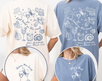May include: Two t-shirts, one cream and one blue, with beach-themed graphics. The back of each shirt features illustrations of seashells, cocktails, and the text "Last toast on the coast." The front of the cream shirt says "Future Mrs. Smith," and the blue shirt says "Chloe's Back."