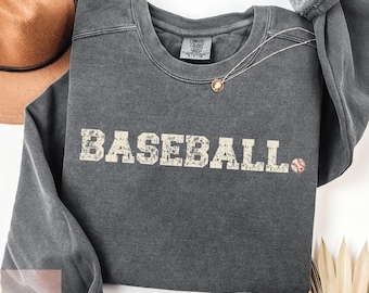 May include: A dark gray sweatshirt with the word "BASEBALL" printed in white with a distressed look. A small baseball graphic is to the right of the word.