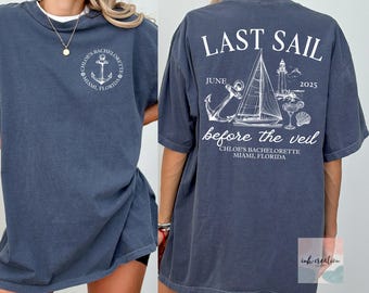 May include: A blue-grey t-shirt with white text and graphics. The front features an anchor design and the text "Chloe's Bachelorette Miami, Florida." The back displays "Last Sail" with a sailboat, lighthouse, and the text "June 2025 before the veil."