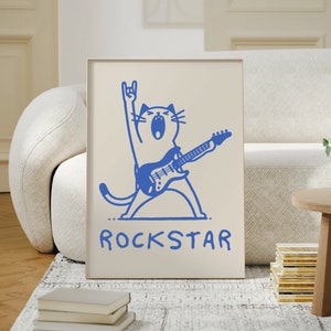Peut inclure: Une illustration bleue d'un chat jouant de la guitare &eacute;lectrique avec le mot "ROCKSTAR" &eacute;crit en dessous.