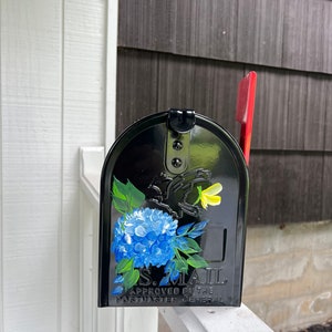 Puede incluir: Buz&oacute;n negro con un dise&ntilde;o floral azul y amarillo. El buz&oacute;n tiene el texto "U.S. MAIL APPROVED BY THE POSTMASTER GENERAL" en la parte delantera.