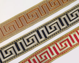 Könnte beinhalten: Drei verschiedene Borten mit einem griechischen Schlüsselmuster. Die Borten sind goldfarben mit braun, schwarz mit silber und rot mit silber.